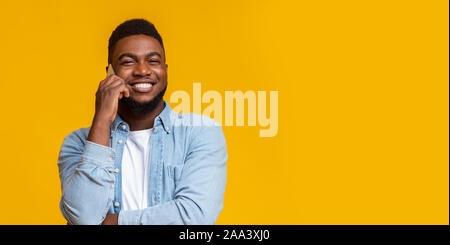 Smirking black man talking on cellphone and looking at camera Stock Photo