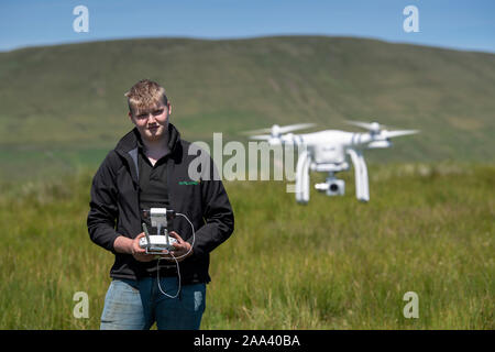 Teenage boy operating a DJI drone in a rural setting, Cumbria, UK. Stock Photo
