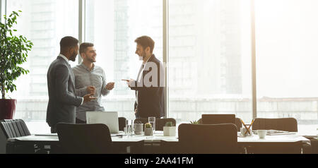 Happy businessmen talking in front of office window Stock Photo