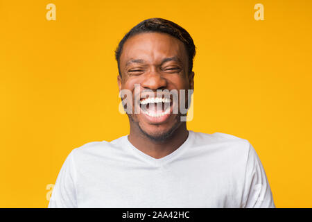 Portrait Of Laughing Black Man Standing Over Yellow Background, Studio Stock Photo