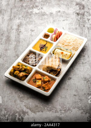 Indian vegaterian Food Thali or Parcel food-tray with compartments in which paneer, dal makhani / parka, aloo-gobi sabji, chapati and rice with Bengal Stock Photo