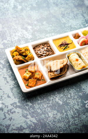 Indian vegaterian Food Thali or Parcel food-tray with compartments in which paneer, dal makhani / parka, aloo-gobi sabji, chapati and rice with Bengal Stock Photo