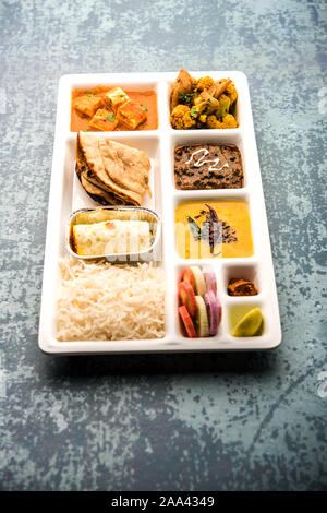 Indian vegaterian Food Thali or Parcel food-tray with compartments in which paneer, dal makhani / parka, aloo-gobi sabji, chapati and rice with Bengal Stock Photo