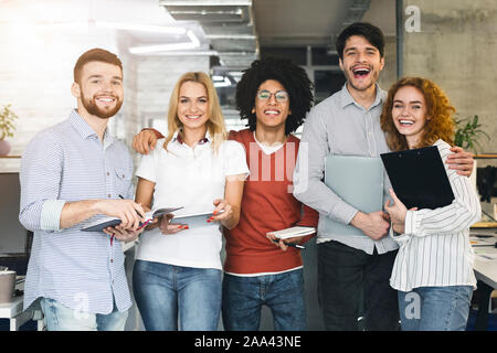 Group of young professionals smiling at camera in office Stock Photo