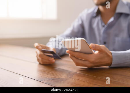 Cropped image of man using credit card and modern smartphone Stock Photo
