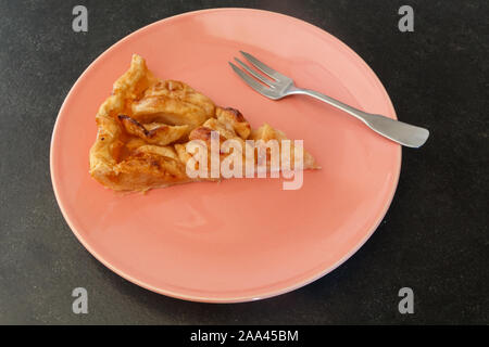 Piece of apple tart and fork on a red plate Stock Photo