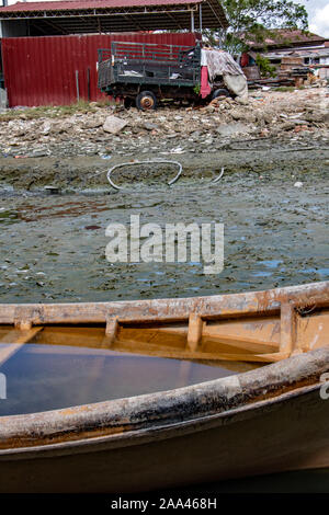 Flooded ship in mud in dry lagoon with damaged lorry in ruins on a background. Abandoned boat at Clan Jetties of George Town, Penang, Malaysia. Stock Photo