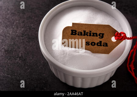 Baking soda in white bowl on black background Stock Photo