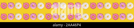 Wide festive creative christmas banner pattern of colorful donuts as Christmas tree toys on yellow background. Xmas decorations. Stock Photo