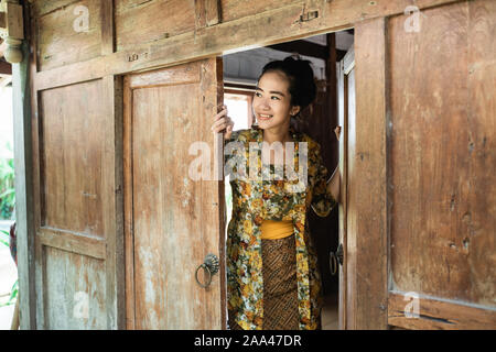 asian young woman wearing a kebaya opens the door Stock Photo