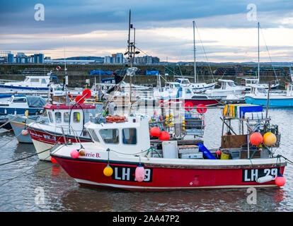 Small fishing boats moored in Newhaven Harbour at sunset on a Winter day, Edinburgh, Scotland, UK Stock Photo