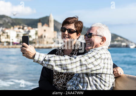 Two seniors using a mobile in Sitges, Spain Stock Photo