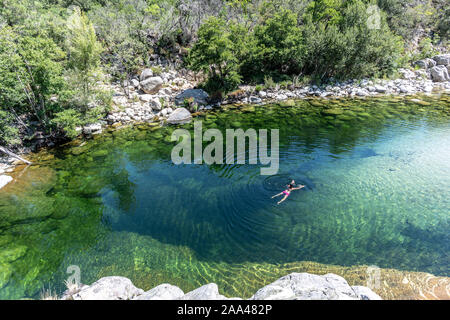 Adult woman swimming in a pure and fresh water natural pool of Travu River, Corsica, France, Europe Stock Photo