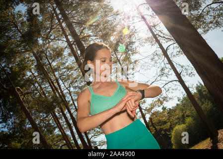 sporty woman checking her pulse and steps on a smart watch after running in the woods. Stock Photo