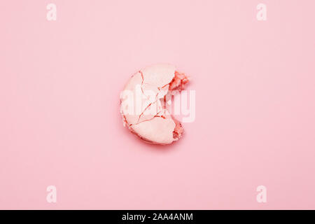 Minimalism, bitten macaroons on pink background, top view. Stock Photo