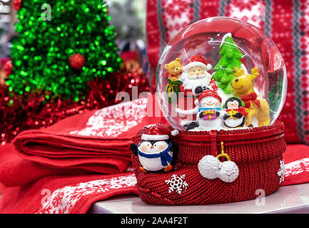 Glass snow globe with Santa Claus, deer, penguin, christmas tree and snowman inside. Stock Photo