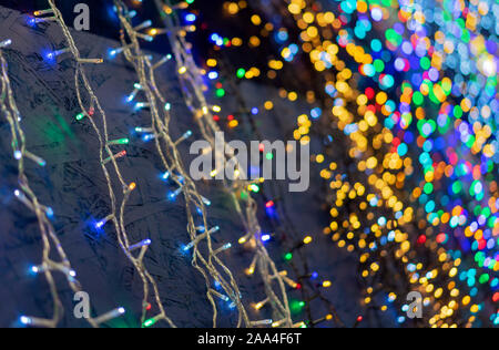Defocused christmas garlands with colorful glow. Christmas background with multicolored bokeh. Stock Photo