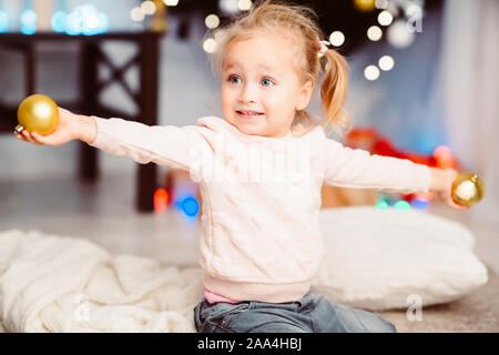 Cheerful little girl playing with Xmas tree decorations Stock Photo