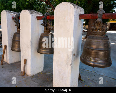 Three large hanging temple bells with mallets of the Shwezigon Pagoda in Bagan, Myanmar (Burma) used to call monks to prayer or ward off evil Stock Photo