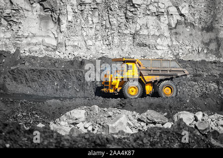 Big yellow mining truck laden anthracite moves open pit coal mine. Stock Photo