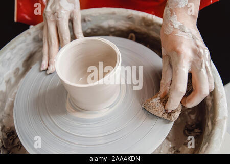Work at potter wheel in apron. Hands of young woman with clay. Top view. Stock Photo