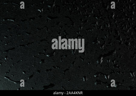macro background of black flat rubber surface with water drops. Stock Photo