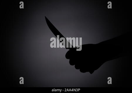 attacking with a knife / melee weapon shadow black silhouette in the dark Stock Photo