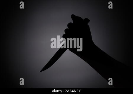 attacking with a knife / melee weapon shadow black silhouette in the dark Stock Photo