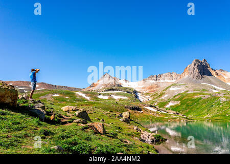Landscape view of green meadow and Ice lake water near Silverton, Colorado in August 2019 summer and man taking picture on summit Stock Photo