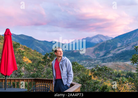 Aspen, Colorado rocky mountains colorful purple blue twilight sunset view and young man standing by deck wooden terrace railing in autumn Stock Photo