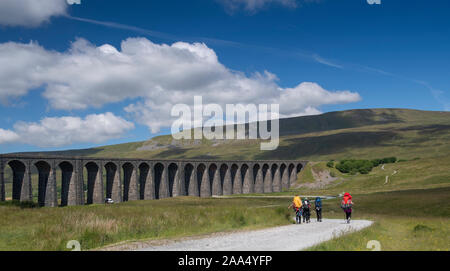 Walkers heading along track towards Ribblehead Viaduct and Whernside, one of the Three Peaks in the Yorkshire Dales National Park, UK. Stock Photo