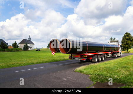 Truck transporting large steel oil and gas pipes, excessive load and heavy delivery concept Stock Photo