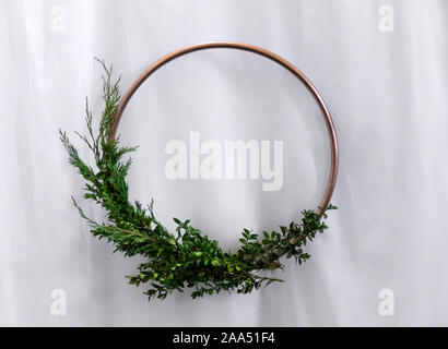 Wedding decorative frame. Bronze circle with boxwood greens and Christmas tree on a white tulle background Stock Photo