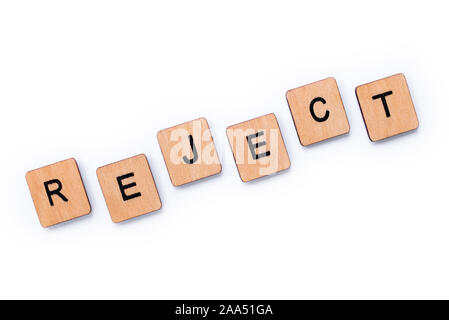 The word REJECT, spelt with wooden letter tiles over a white background. Stock Photo