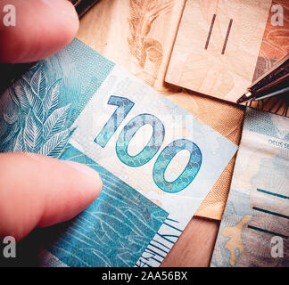 Real - Brazilian Currency. Money bills on a wooden table and a man holding a banknotes. Stock Photo