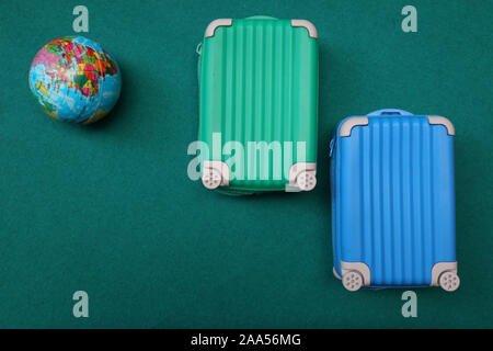 Flat lay two suitcase with a globe on green bright background. travel concept Stock Photo