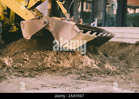 Excavator moving earth with the shovel on the construction site Stock Photo