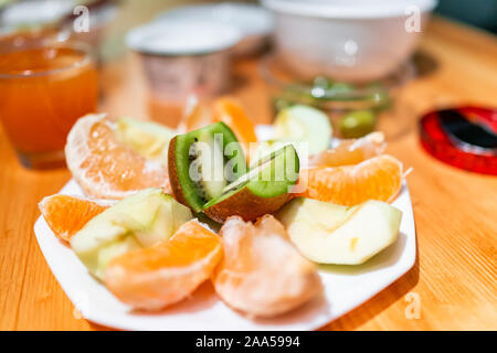 White plate of sour foods sliced fruit serving setting on wooden table for breakfast with kiwi, grapefuit and green apple Stock Photo