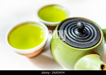 Kyusu teapot and two cups filled with Japanese vibrant green yellow sencha fukamushi or genmaicha tea color against white background Stock Photo