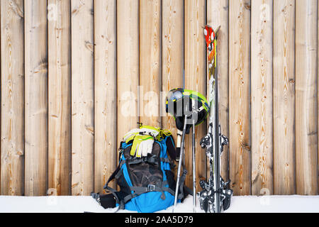 Skis, helmet, backpack at ski resort on background of wooden fence in afternoon Stock Photo
