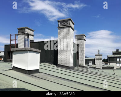 Chimneys and vents on the tin roof of the building. A chimney is an architectural ventilation structure made of masonry, clay or metal. Stock Photo