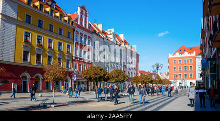 Unidentified tourists walking along the colorful houses of the Swidnicka street. The Swidnicka is one of Wroclaws main streets. Wroclaw, Poland. Stock Photo