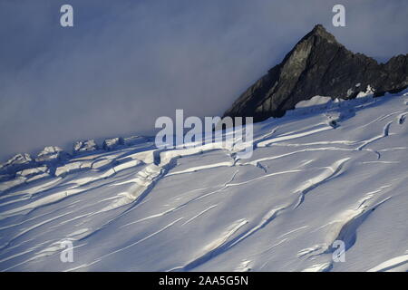 Aerial photo of a rocky spire and a crevasse filed glacial snowfield in the Chugach Mountains, Alaska Stock Photo