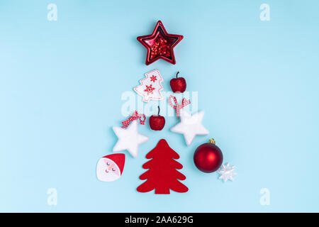 New Year and Christmas composition in the form of chrismas tree. Red and white decorations - stars, christmas balls, toys on pastel blue paper background. Top view, flat lay, copy space Stock Photo