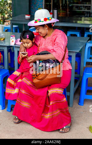 A Burmese Grandmother Looks On With Pride As Her Granddaughter Uses A Mobile Phone (Cellphone), Pindaya, Shan State, Myanmar. Stock Photo