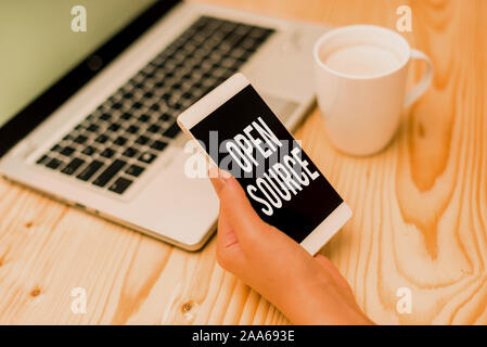 Writing note showing Open Source. Business concept for denoting software which original source code is made free woman with laptop smartphone and offi Stock Photo