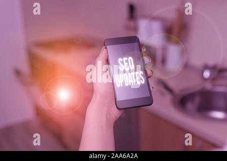 Conceptual hand writing showing Seo Updates. Concept meaning new information or design in search engine optimization woman using smartphone and techno Stock Photo