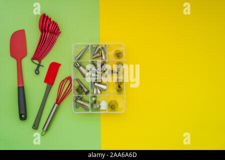 Baking utensils and a box of piping nozzles on flat lay, green yellow background Stock Photo