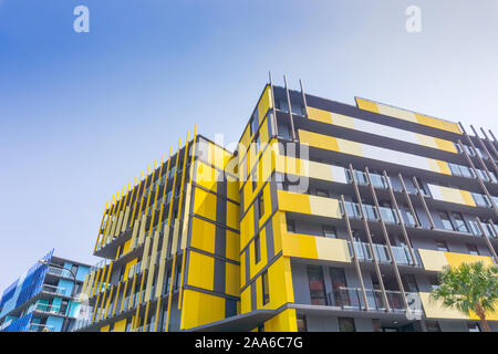 Gold Coast Australia - November 19 2019; Exterior of striking yellow and blue  apartment blocks and commercial building shot from street below looking Stock Photo