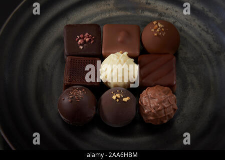 A pile of exquisitely beautiful chocolate cubes placed on a dark grey ceramic plate with a water ripple. Stock Photo